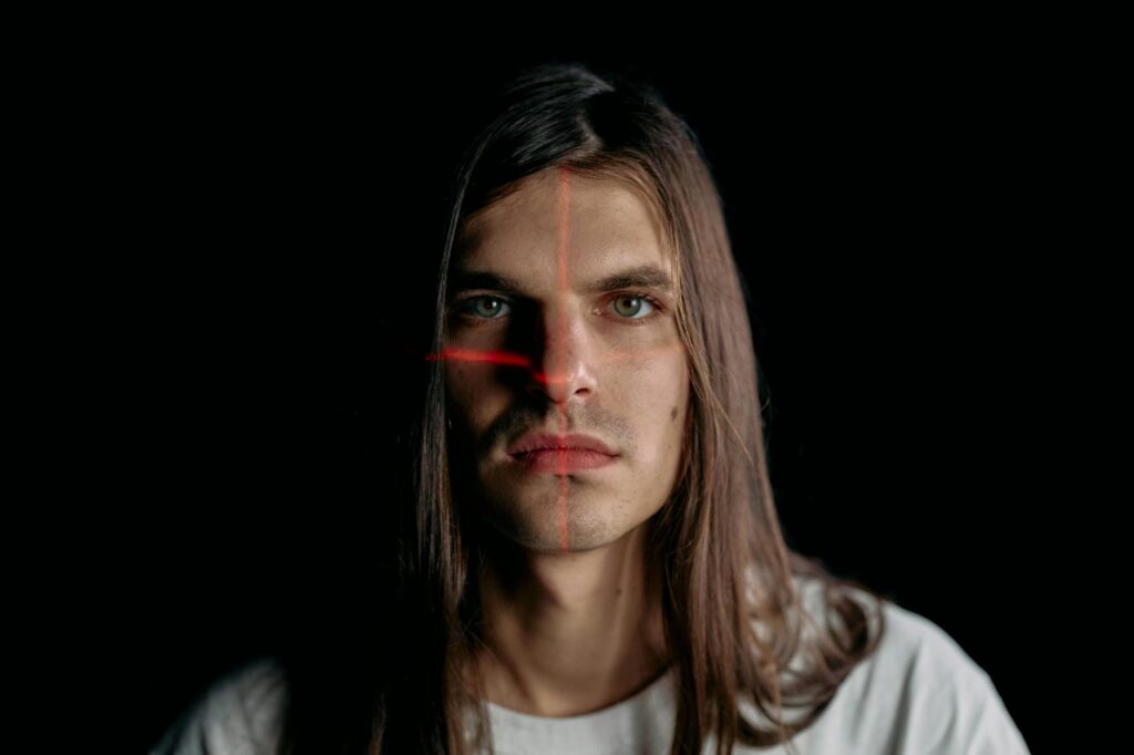 Studio portrait of a man with long hair featuring a facial recognition laser grid.