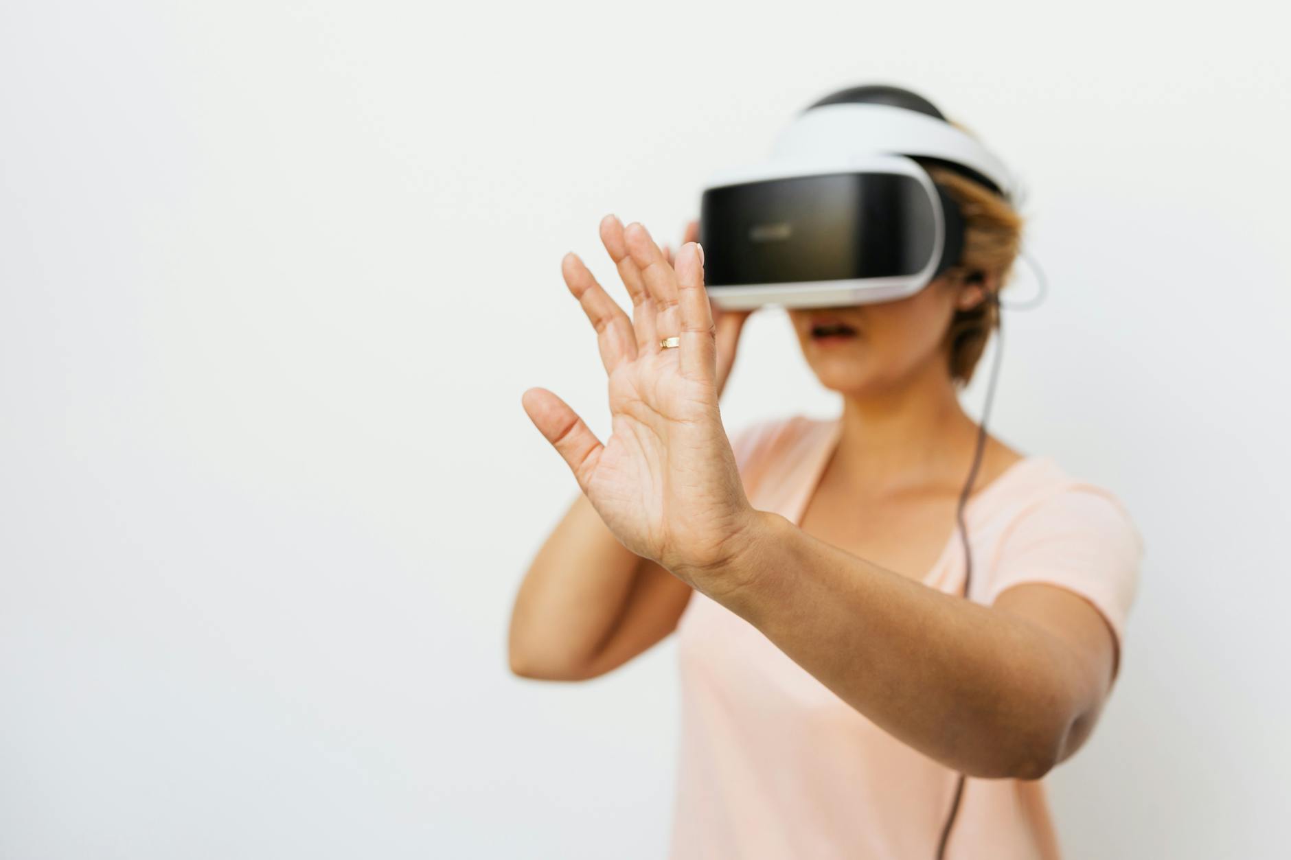 A woman using a VR headset interacts in a virtual reality environment indoors.