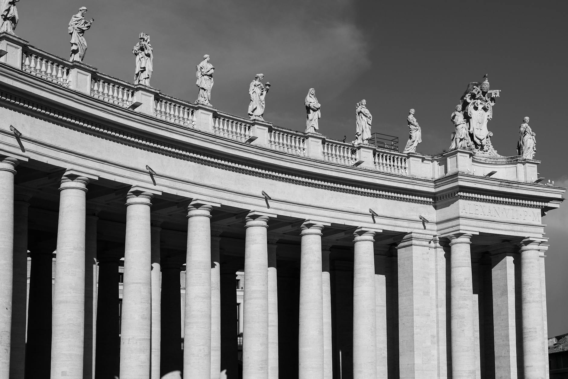 Black and white image of St. Peter's Basilica colonnade with statues.