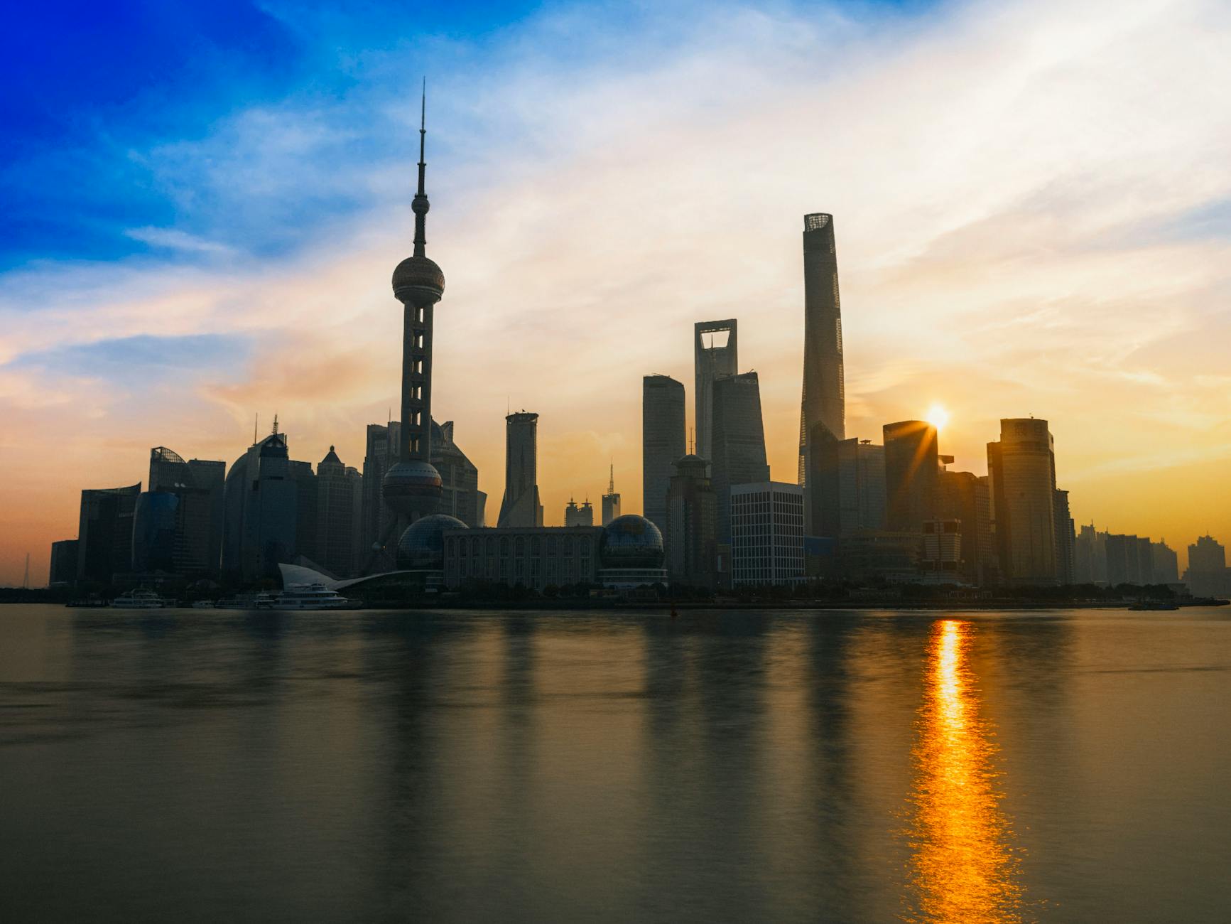 Captivating sunset view of the Shanghai skyline with iconic skyscrapers reflected on the waterfront.
