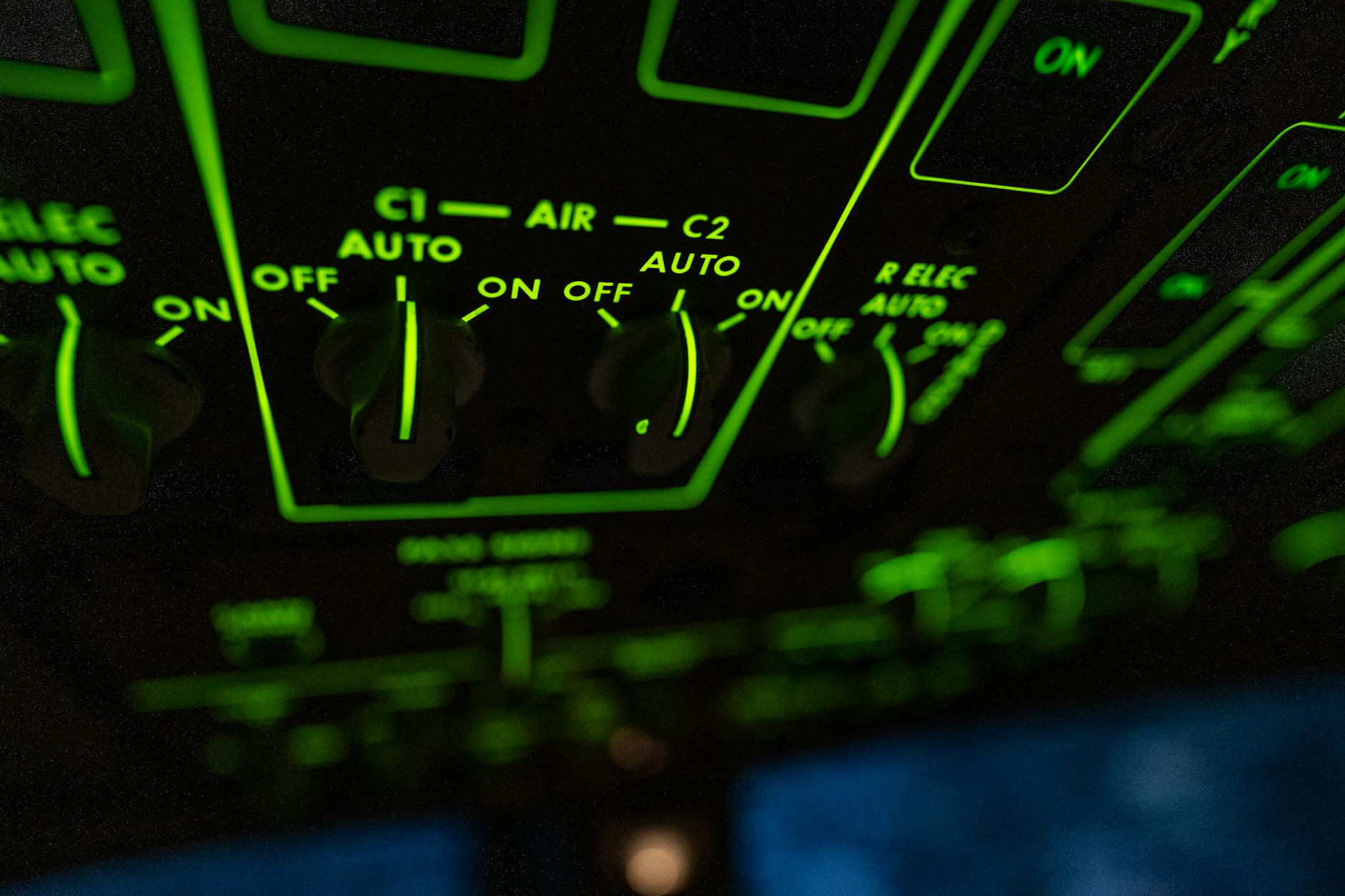 Close-up shot of illuminated aircraft cockpit controls with green lighting.