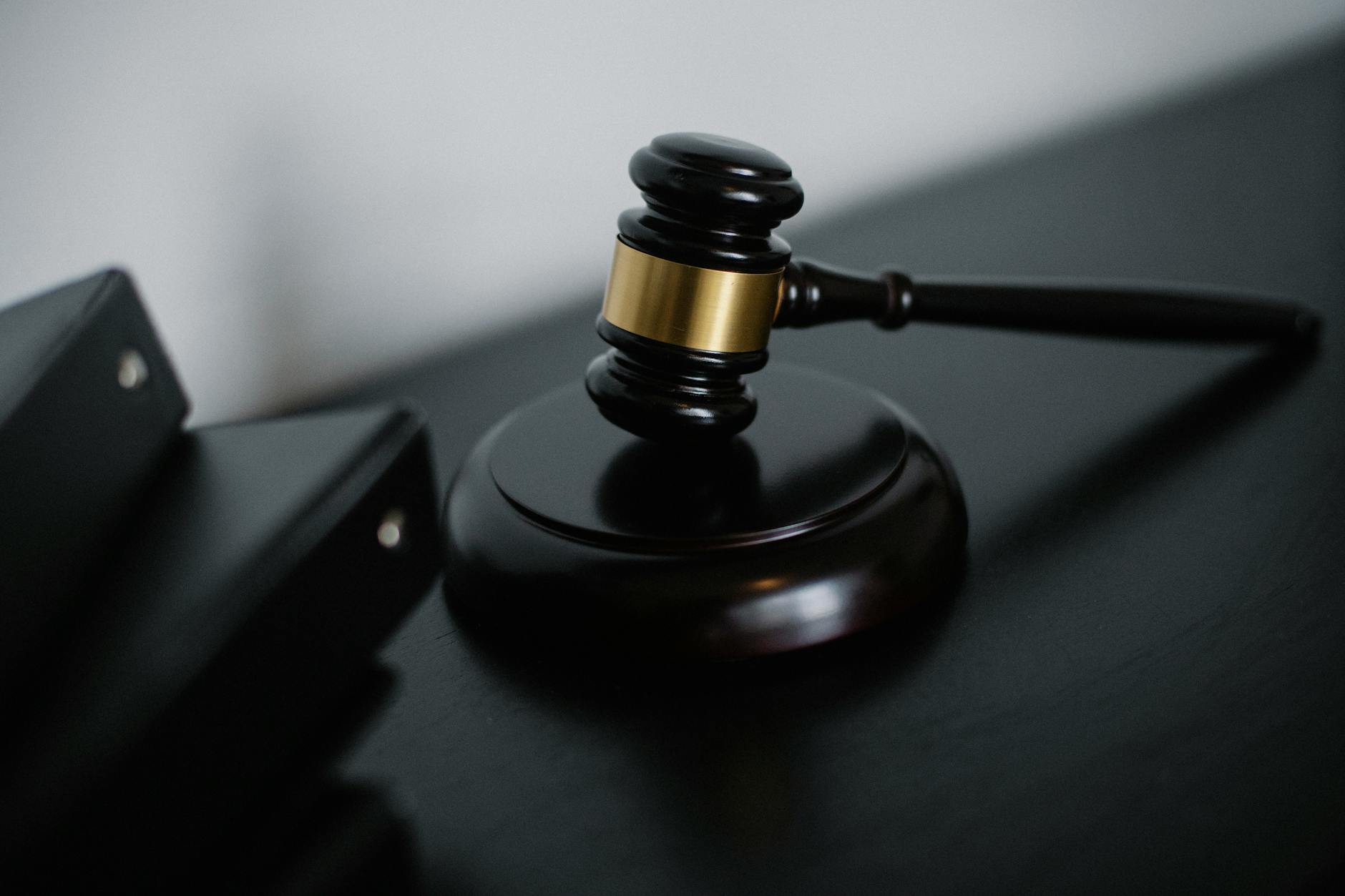 High angle of shiny wooden ceremonial mallet with golden detail placed on judge tale near documents folders