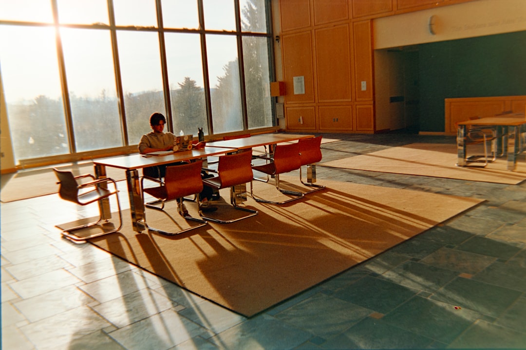 Futuristic AI ethics committee meeting in sleek glass conference room, holographic neural network display, ambient blue lighting, diverse professionals in discussion, clean modern university campus vi