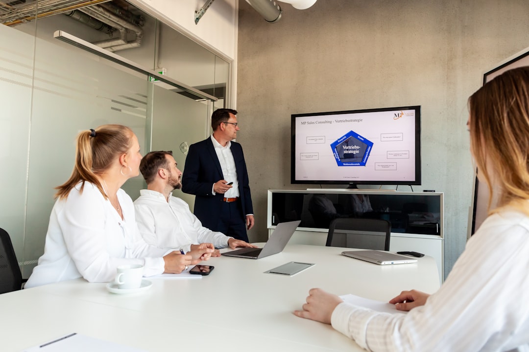 Clean modern office with military officials and tech engineers collaborating, holographic display of AI regulation documents, cool-toned professional lighting, cybersecurity dashboard visible, human-r