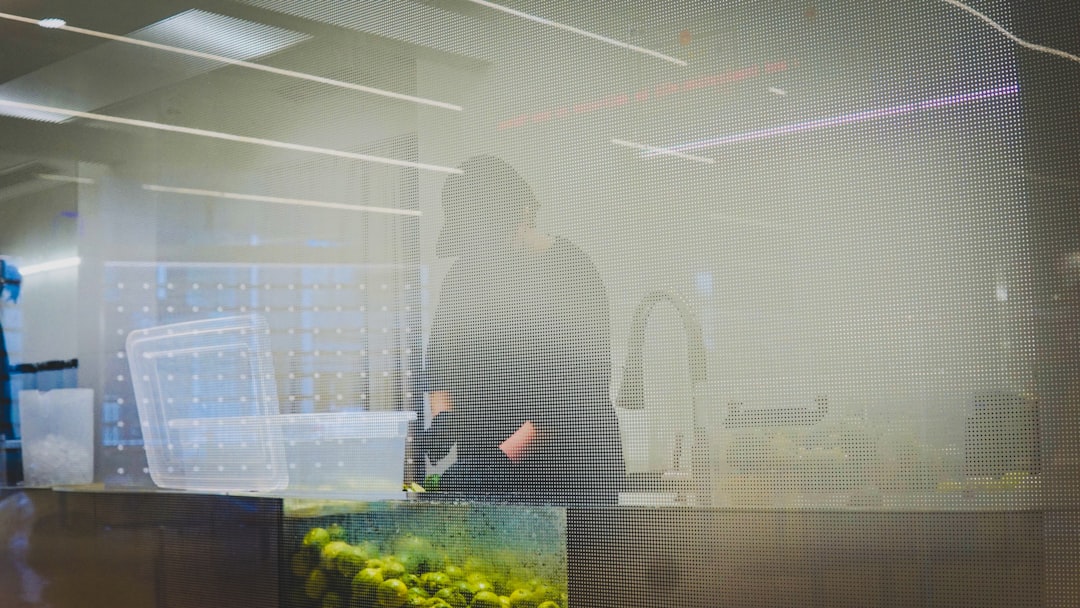 A futuristic, sleek professional in a clean modern office interacts with a floating holographic display showing neural network visualization, ambient lighting in cool blues and silvers, data center vi