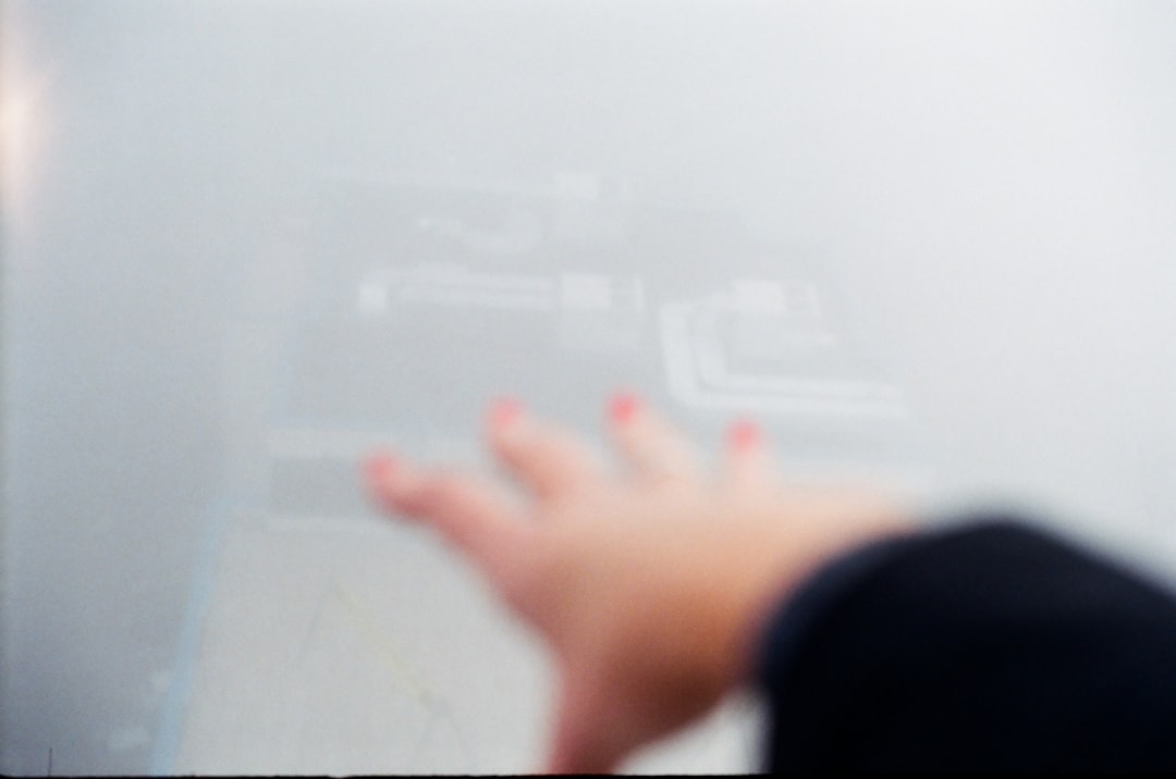 Futuristic human hand touching holographic neural network visualization floating above sleek server room, ambient blue-purple lighting, clean modern data center, professional tech engineer in backgrou