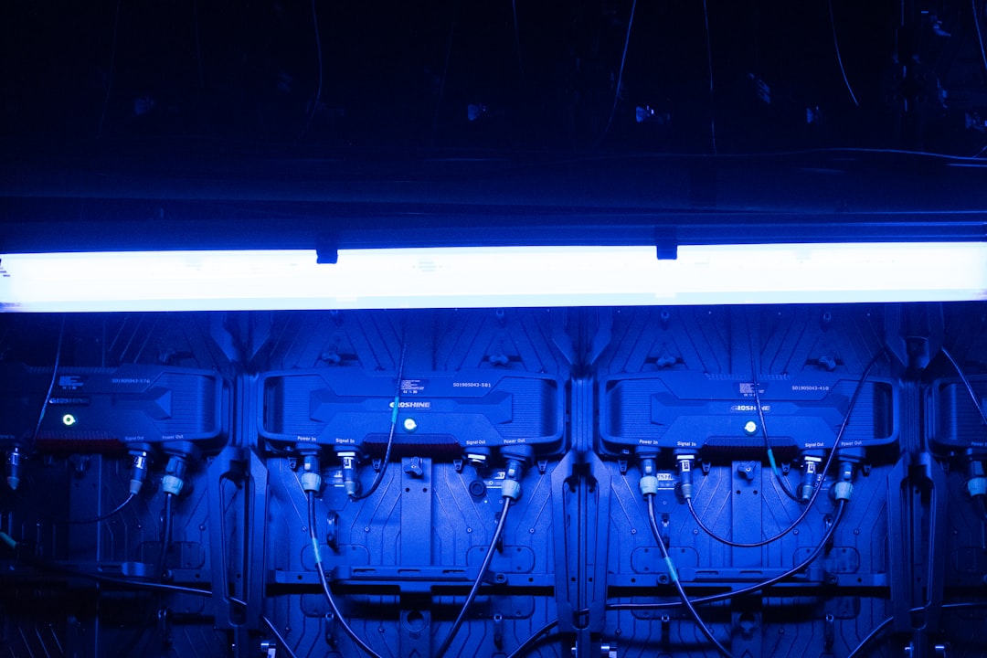 Overcrowded vintage server room with flickering blue lights, exhausted technician in shadows, cables tangled, heat waves rising, symbolizing outdated data center infrastructure failure