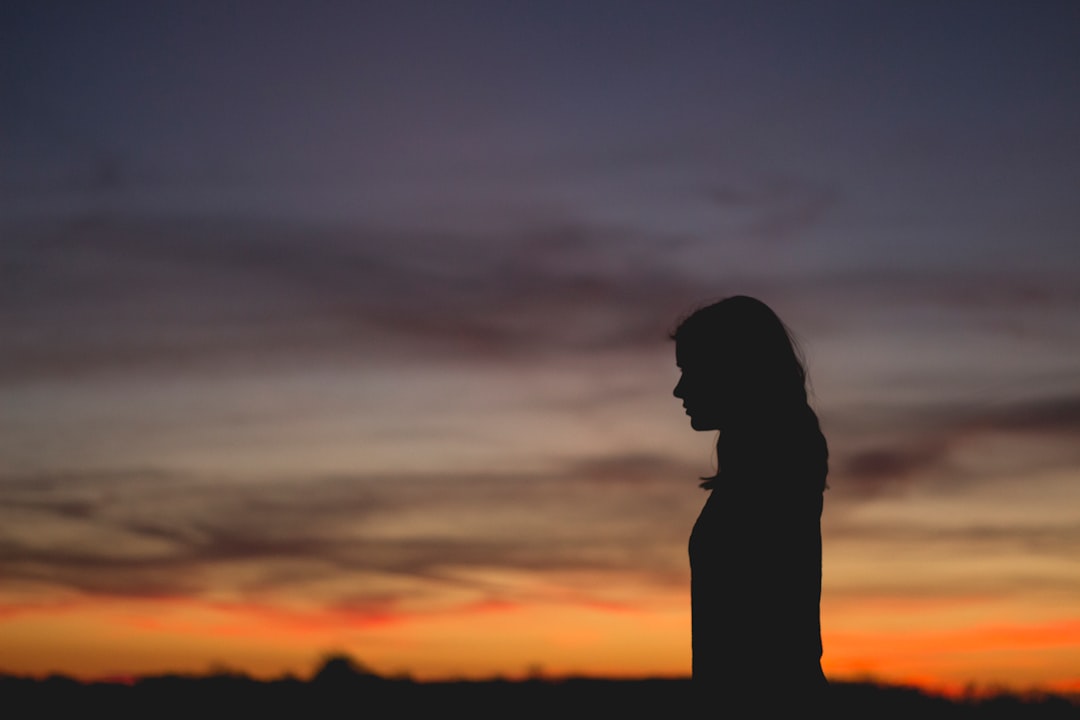 Silhouette of professional woman observing silent AI server farm through glass wall, minimalist futuristic architecture, soft diffused lighting, human-robot collaboration concept, contemplative mood, 