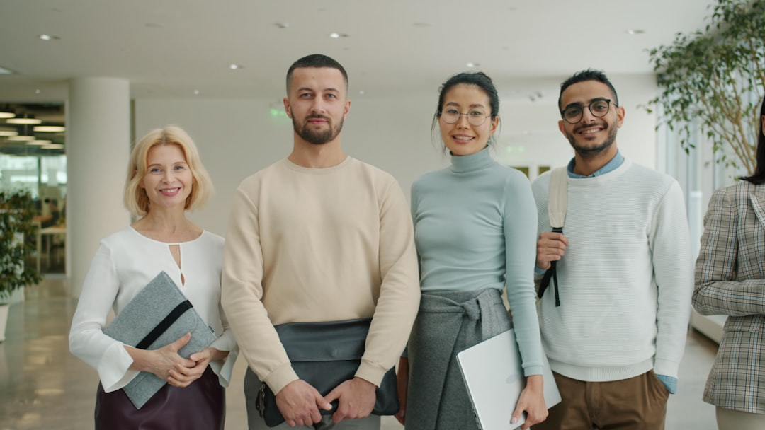 Diverse group of professionals in sleek suits gathered around holographic display showing interconnected global nodes, warm ambient lighting, glass-walled multilateral conference room, human-robot col