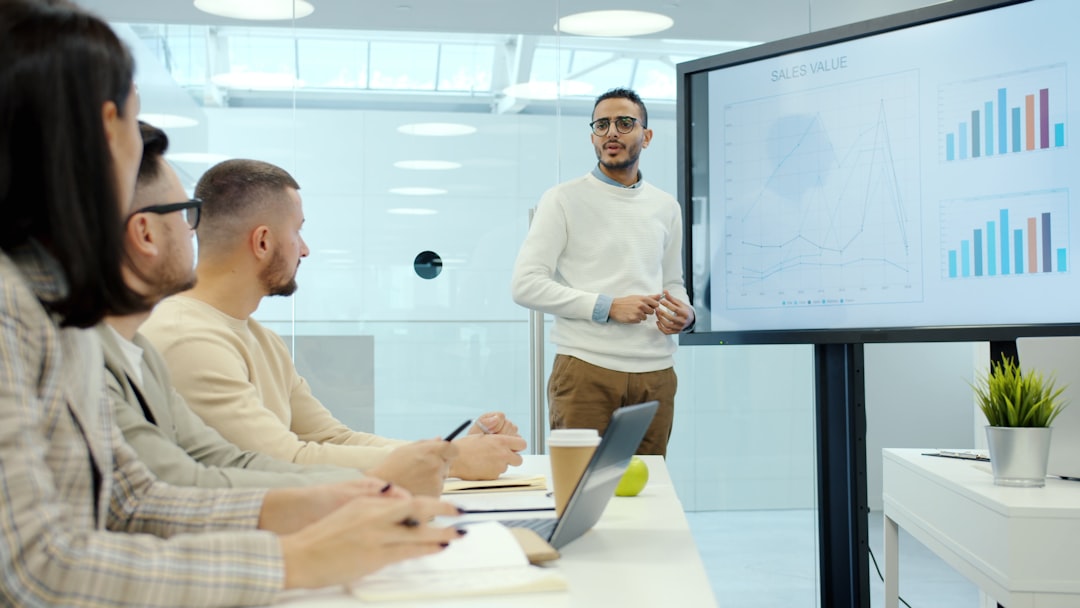 Professional data analyst presenting economic impact charts on curved holographic display, server room background with ambient cyan lighting, diverse team observing social metrics, sleek glass table, 