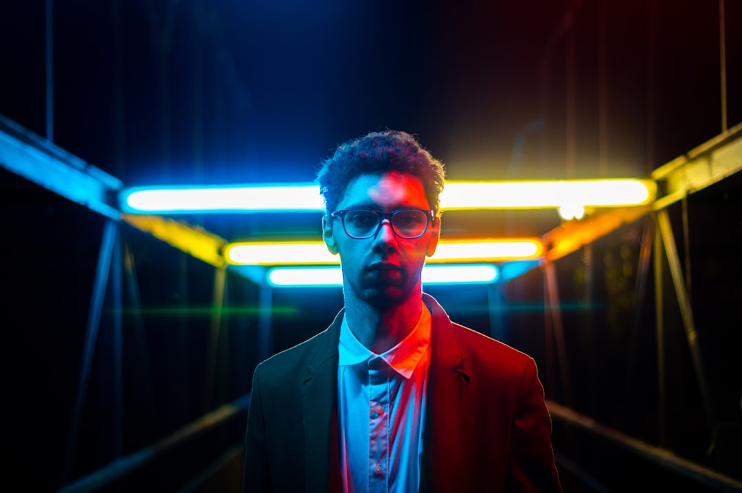Financial analyst in tailored suit examining holographic stock market visualization with AI prediction curves, sleek trading floor with ambient green and gold lighting, microchip detail reflections on