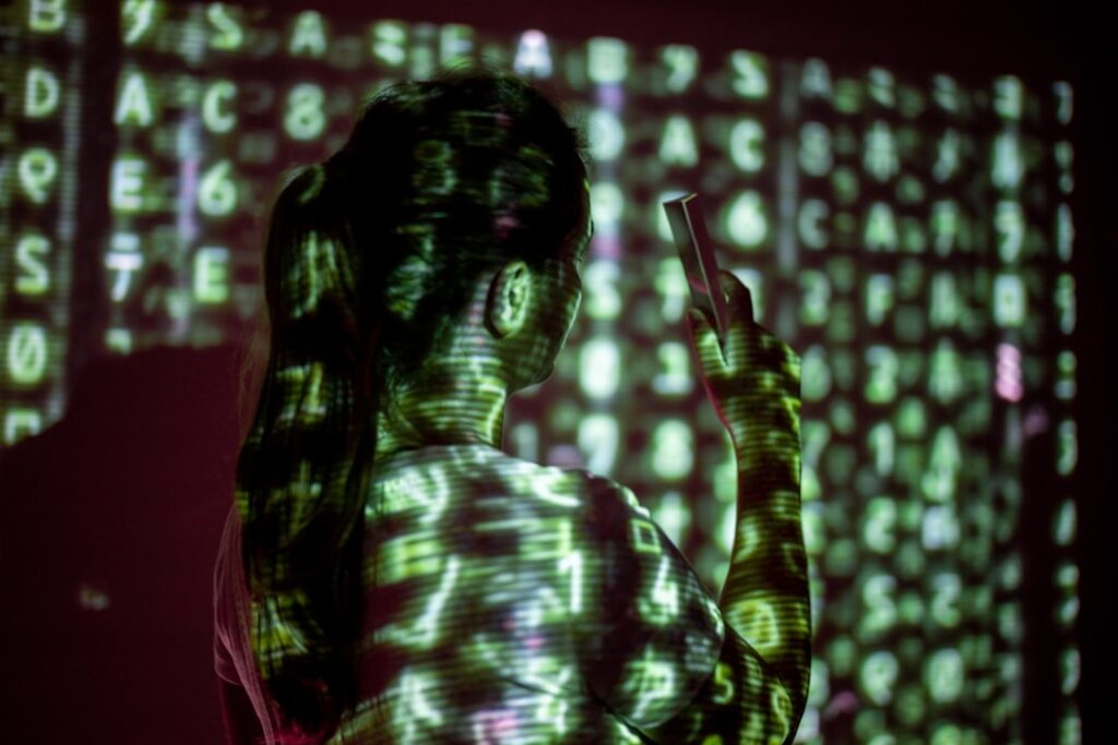 Futuristic cybersecurity dashboard with red alert glow, silhouette of professional woman viewing holographic election data, dark server room ambient lighting, democracy threat concept