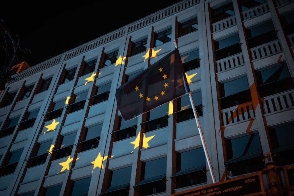 Futuristic European Union flag hologram projected over sleek data center server racks, professional ambient blue lighting, tech executive observing global compliance dashboard