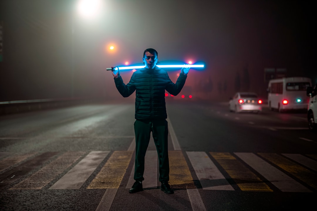 Young professional standing at crossroads between robotic automation arm and glowing holographic skills chart, moody blue ambient lighting, futuristic corporate atrium, cinematic depth of field