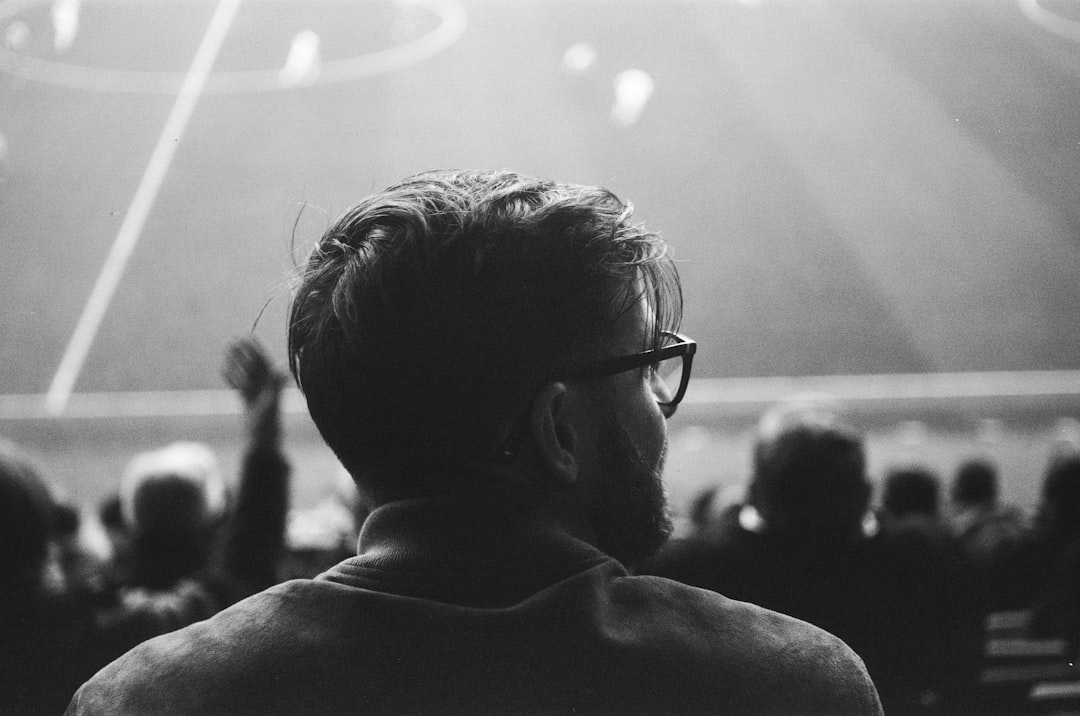 Diverse crowd wearing AR glasses watching holographic soccer match, immersive stadium experience, privacy symbol overlay, sleek futuristic design, ambient purple and teal lighting
