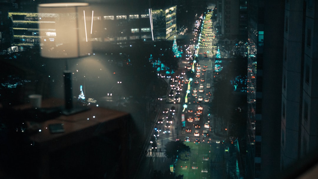 Futuristic AI surveillance dashboard with holographic data visualization in sleek glass office, Latin American city skyline at dusk, ambient blue neon lighting, professional analyst silhouette