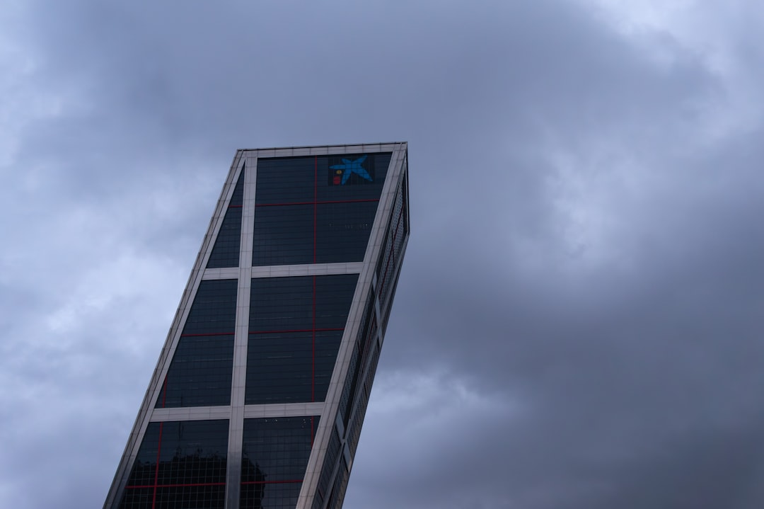 Futuristic sleek glass government building with holographic AI regulation interface floating above, ambient blue lighting, professional figures examining digital framework, neural network visualizatio