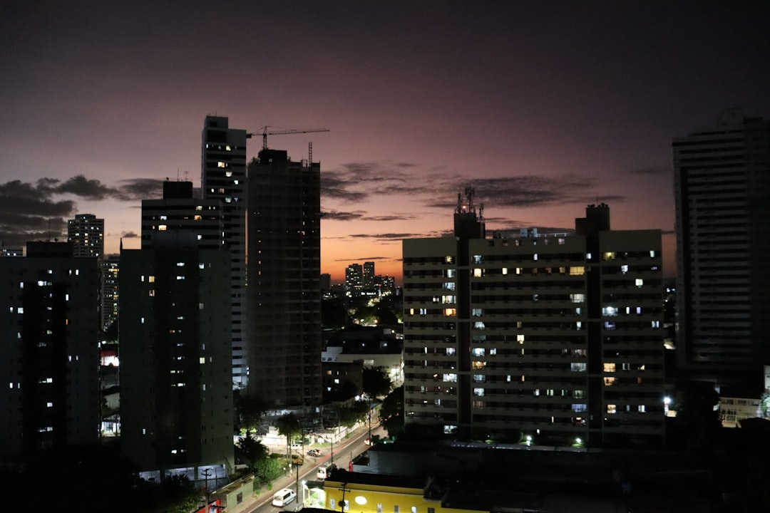 Brazilian cityscape at dusk with holographic AI interface overlaying skyline, diverse professionals collaborating around transparent data dashboard, ambient warm and cool lighting contrast, neural net