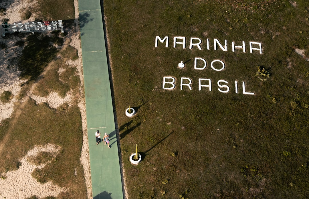 Aerial view of modern Brazilian university campus merging with digital overlay, diverse students using tablets under warm sunset lighting, socioeconomic growth charts holographically projected above N