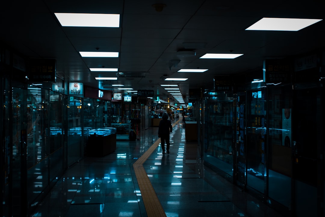 High-performance AI server room with blue ambient glow, neural network pathways overlay, technician monitoring infrastructure on transparent holographic dashboard