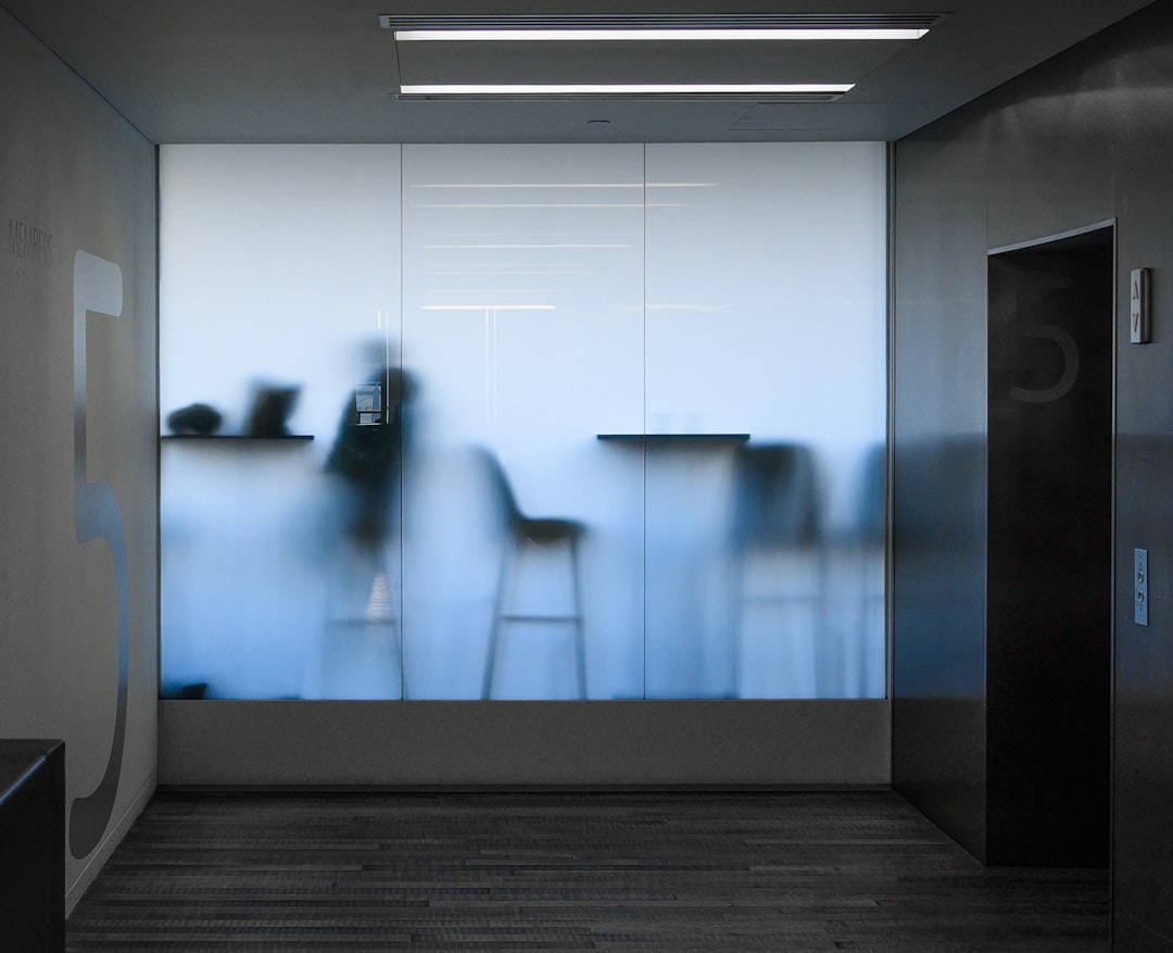 Futuristic professional with holographic AI assistant in sleek glass office, ambient blue lighting, neural network visualization floating between human and machine collaboration
