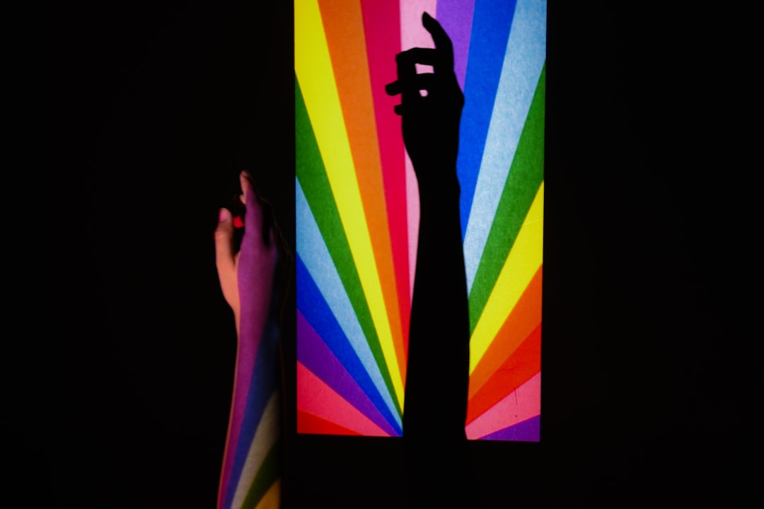 Close-up of hands touching immersive multimodal display with flowing data visualizations, vibrant color spectrum light rays, professional setting, sensory technology experience, sleek futuristic inter