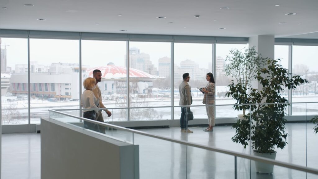 Futuristic corporate lobby with holographic AI assistant interacting with professional woman, sleek ambient lighting, neural network visualization floating in air, clean modern office, dawn atmosphere