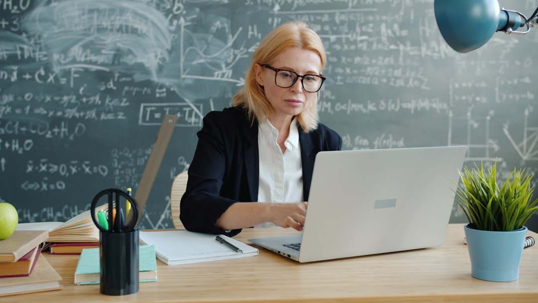 Futuristic cloud computing education concept, holographic neural network floating above sleek laptop, diverse students in ambient blue light, clean modern university lab with data visualization screen