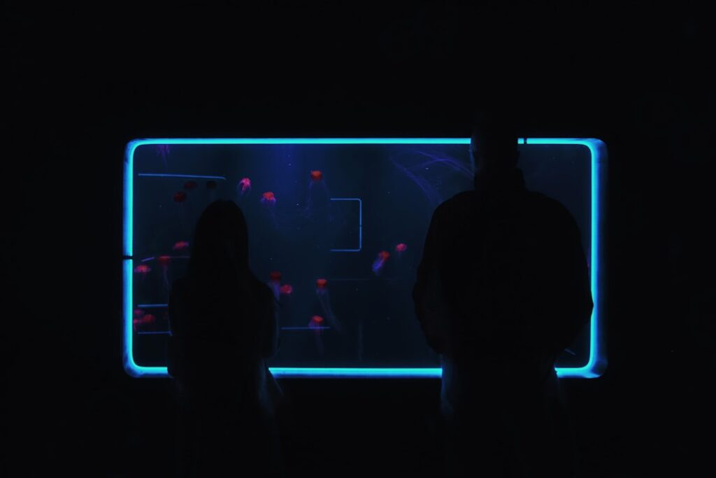 Young diverse professionals staring worriedly at holographic data visualization of declining trust metrics in sleek dark futuristic office with blue ambient lighting