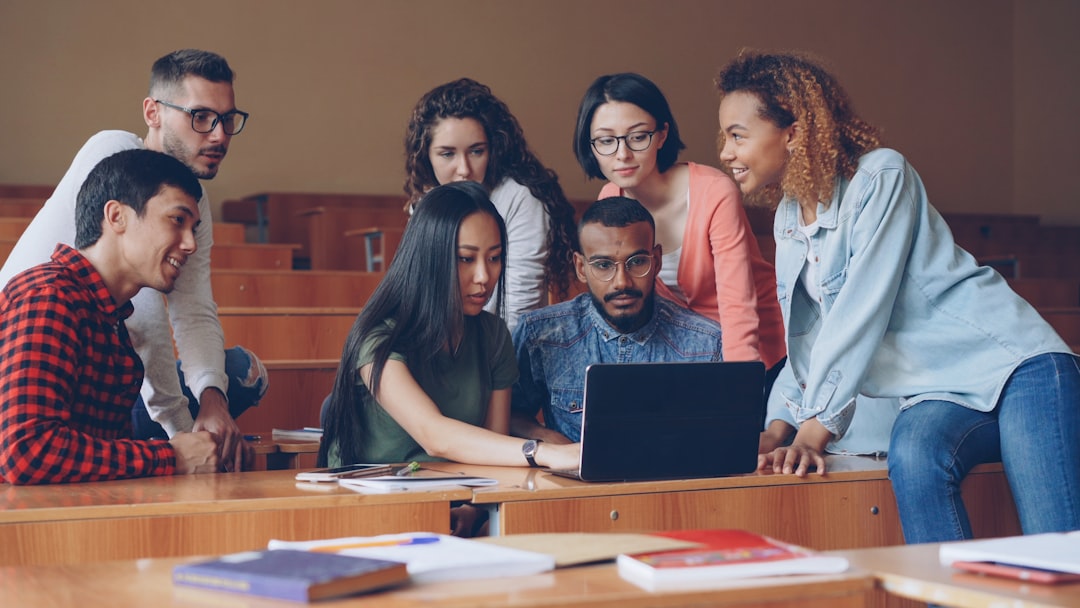 Diverse group of international students and educators gathered around immersive AI ethics concept installation with glowing microchip detail and global connectivity visualization in minimalist tech ca