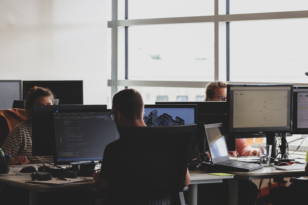 Diverse cybersecurity team collaborating around holographic governance dashboard, sleek server room with green status lights, human-AI interface showing compliance progress bar
