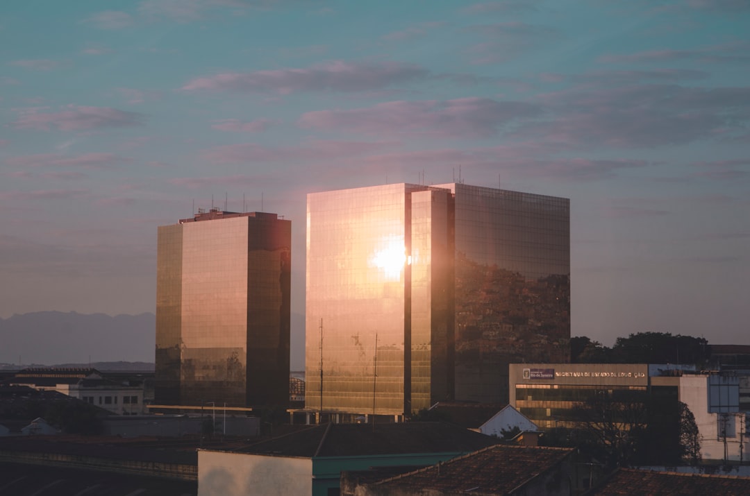 Aerial view of futuristic Brazilian university campus at golden hour with holographic data overlays, modern glass architecture, students walking, ambient teal and amber lighting, regional development