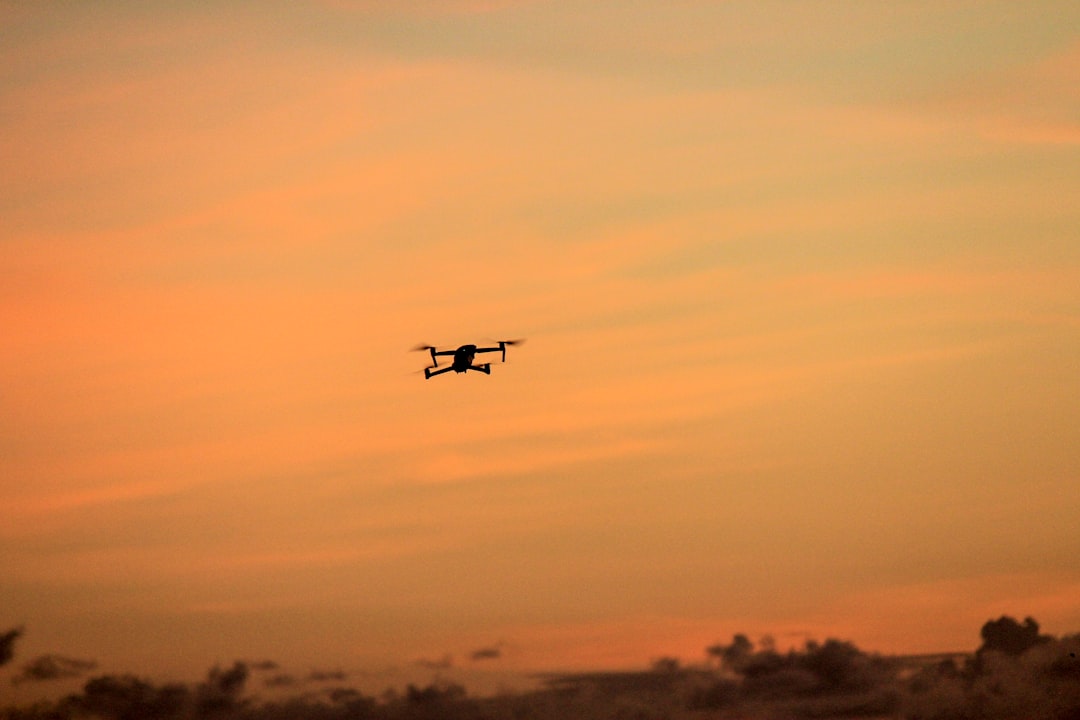 Aerial view of autonomous drone swarm silhouetted against sunset sky, dramatic orange and purple gradients, technological warfare concept, motion blur, cinematic composition
