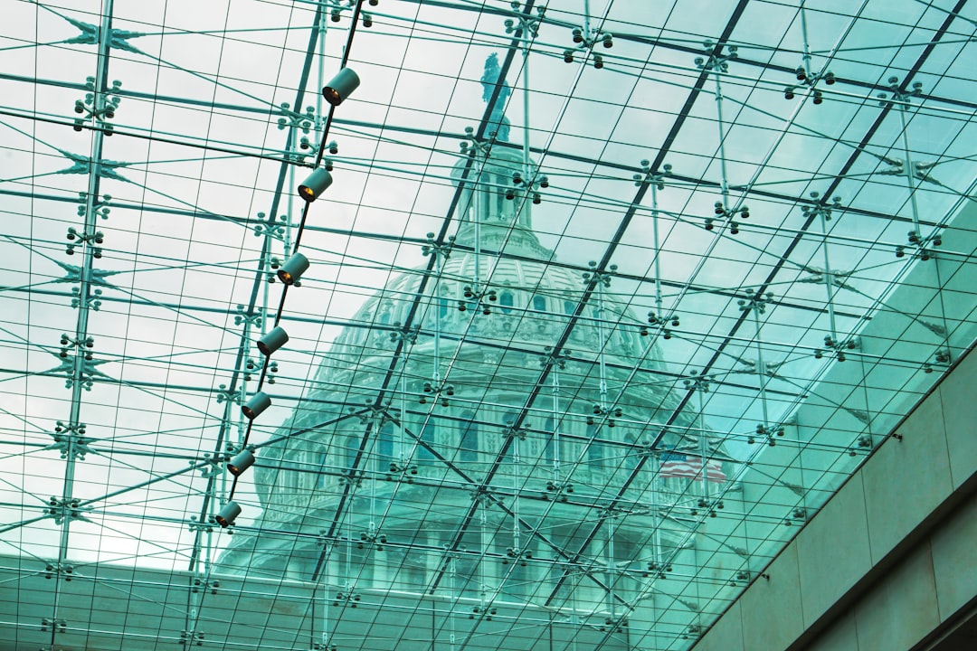 Transparent glass civic center with citizen interacting with AI touchscreen kiosk, warm golden ambient lighting, holographic public data displays, diverse professionals collaborating in background
