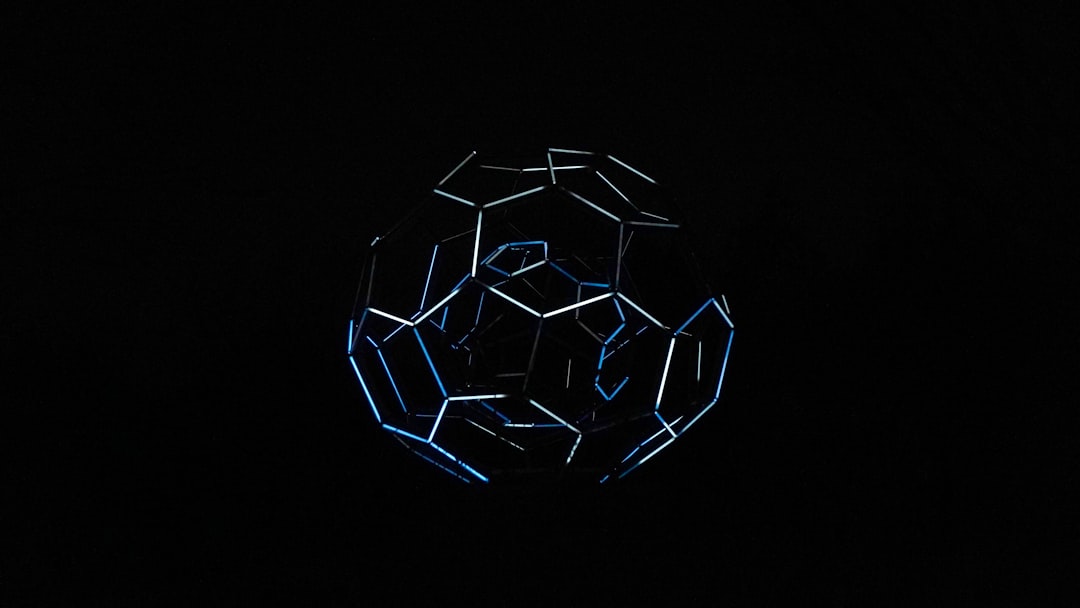 Close-up of a futuristic smart soccer ball with exposed microchip circuitry and glowing sensor arrays, dramatic blue ambient lighting, shallow depth of field, dark technical background with holographi