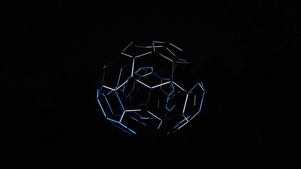 Close-up of a futuristic smart soccer ball with exposed microchip circuitry and glowing sensor arrays, dramatic blue ambient lighting, shallow depth of field, dark technical background with holographi