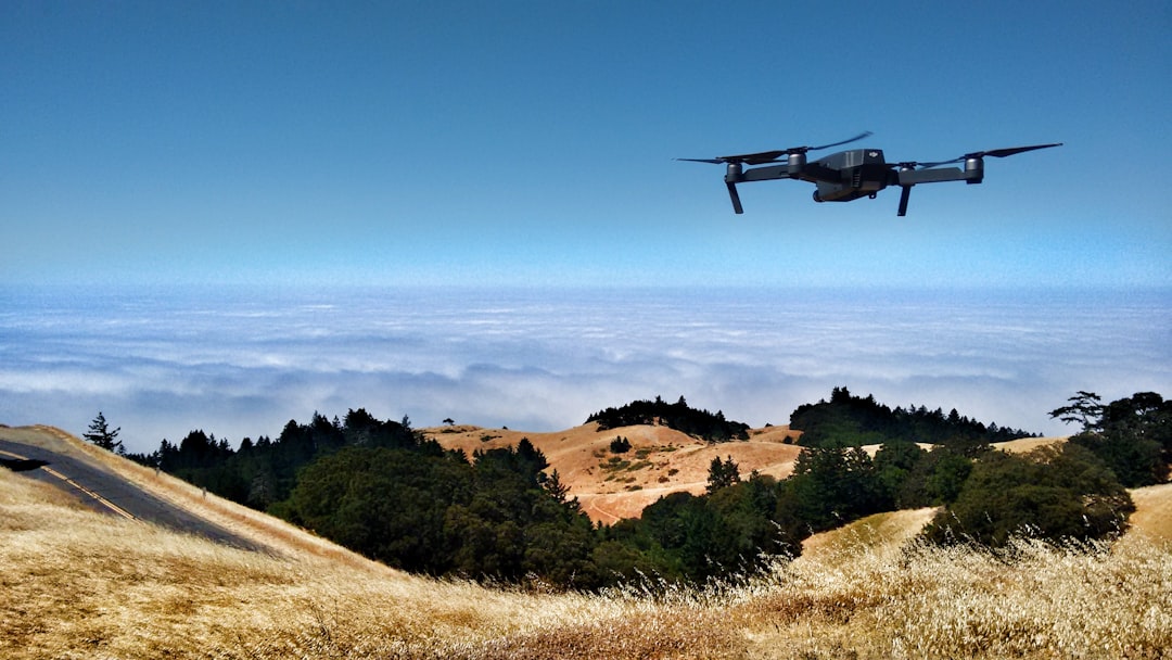 Sleek autonomous drone with holographic facial recognition overlay, dramatic blue ambient lighting, military command center background, futuristic tech aesthetic, human operator silhouette