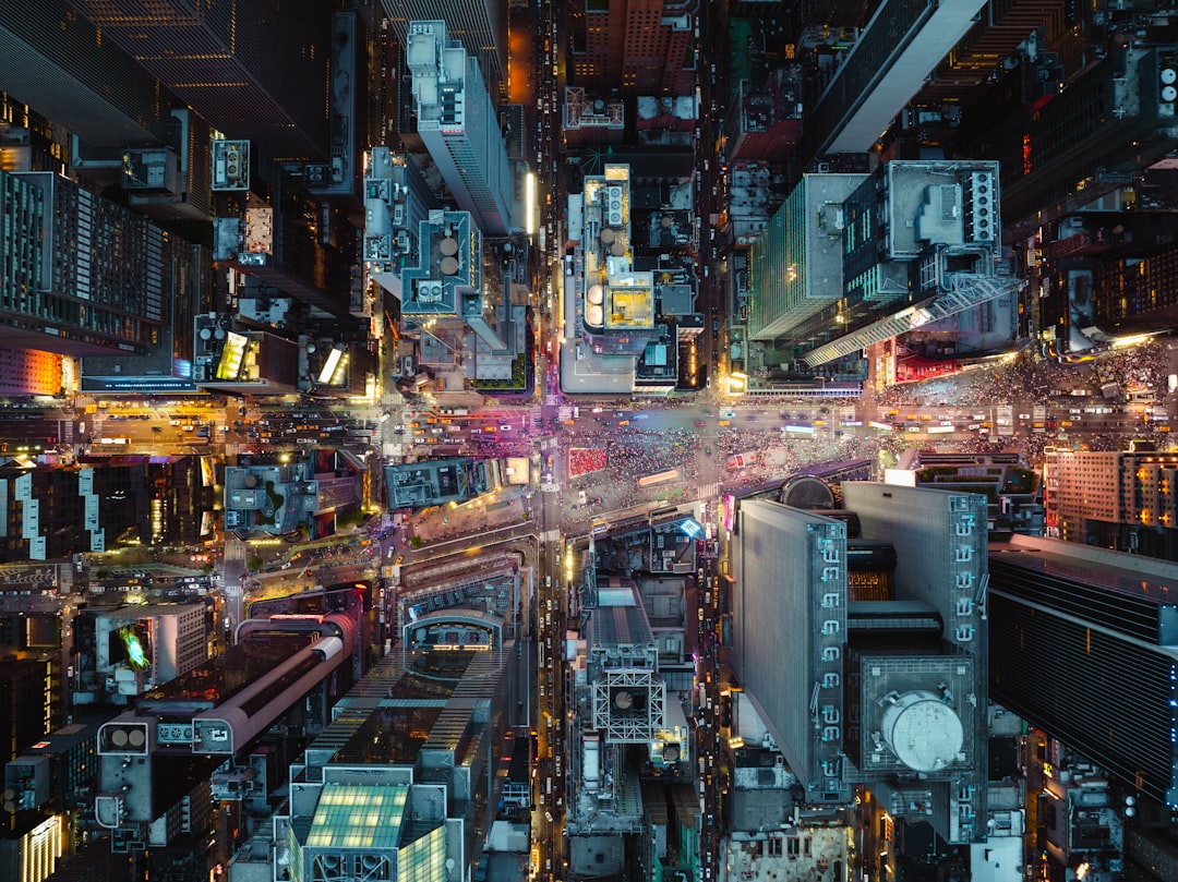 Aerial view of futuristic hyperscale data center with neon blue cooling systems, rows of server racks, technician inspecting microchip detail, sleek industrial architecture