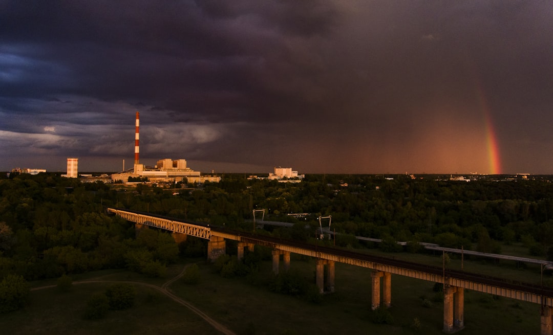 Giant industrial power plant with data center complex, dramatic storm clouds, energy grid visualization, warning lights, tension between ambition and crisis, cinematic composition