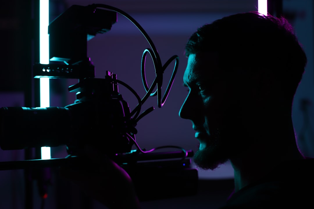 Futuristic film director silhouette collaborating with holographic AI interface, cinematic blue and amber ambient lighting, sleek modern studio, neural network visualization overlaying storyboard