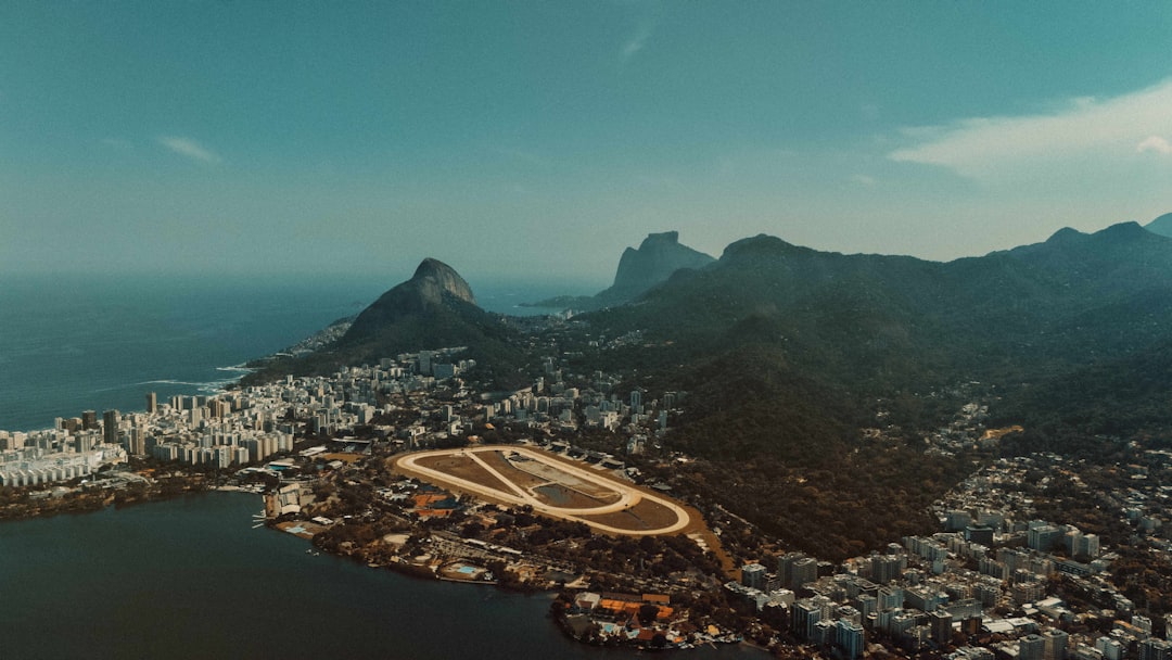 Futuristic Rio de Janeiro urban mobility command center, holographic traffic flow visualization over city map, autonomous vehicle data streams, diverse Brazilian technicians at curved glass workstatio