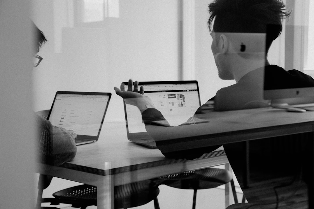 Clean modern office with professional collaborating with holographic AI interface, sleek glass displays showing task management flow, ambient warm lighting, human-robot collaboration in corporate Appl