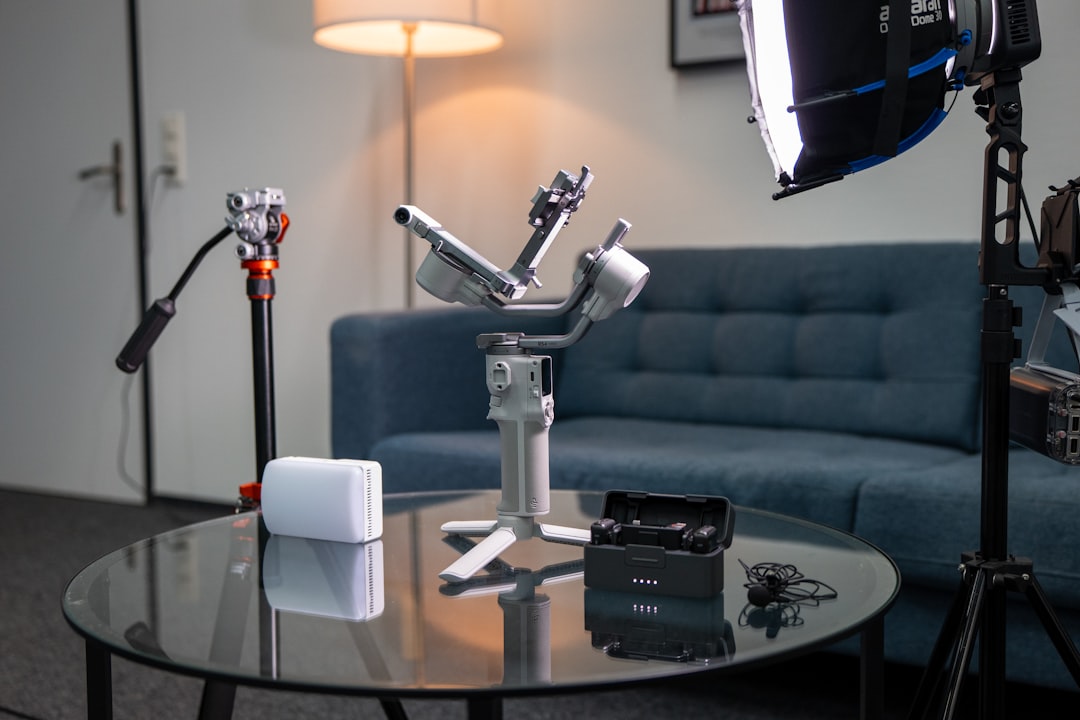 Human photographer and robotic arm collaborating over camera equipment with holographic editing interface in professional studio with dramatic rim lighting