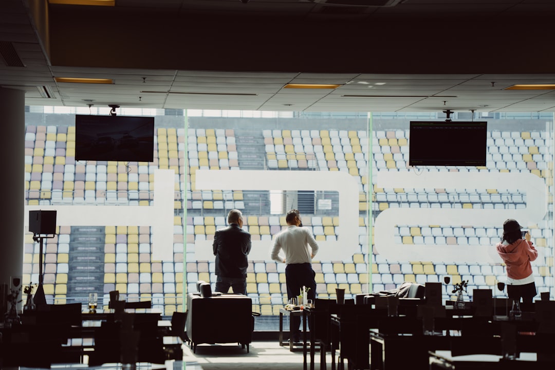 Futuristic sports marketing command center with holographic fan data visualizations, sleek ambient lighting, professional team analyzing real-time engagement metrics on curved displays