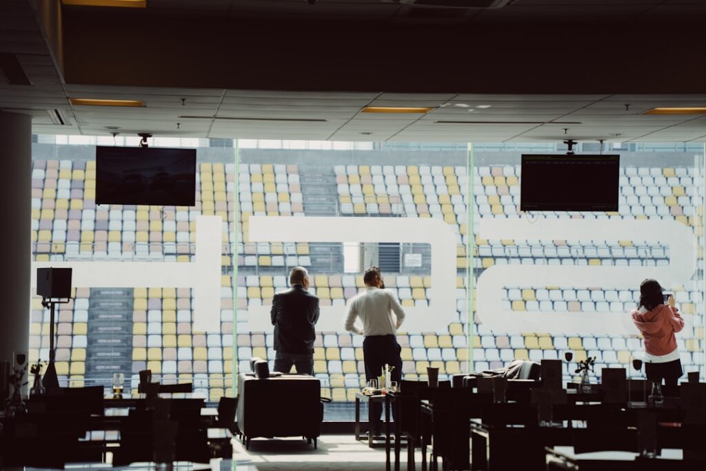 Futuristic sports marketing command center with holographic fan data visualizations, sleek ambient lighting, professional team analyzing real-time engagement metrics on curved displays