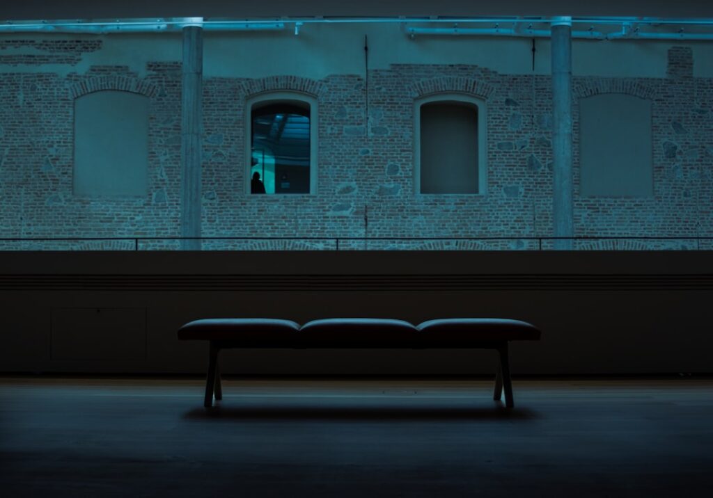 Futuristic Brazilian courthouse interior with sleek holographic AI interface floating above wooden bench, ambient blue lighting, professional robed figure interacting with transparent data display, cl