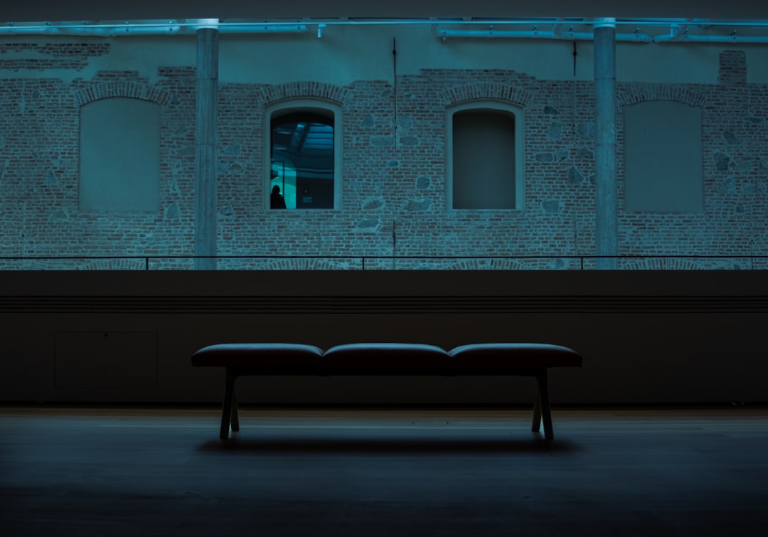 Futuristic Brazilian courthouse interior with sleek holographic AI interface floating above wooden bench, ambient blue lighting, professional robed figure interacting with transparent data display, cl