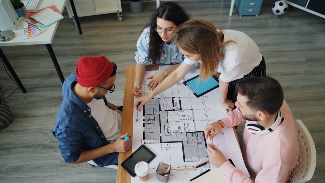 Diverse team of engineers gathered around a holographic display showing real-time adaptive AI systems, wearing sleek professional attire, in a data center with cool blue-green server room lighting, dy