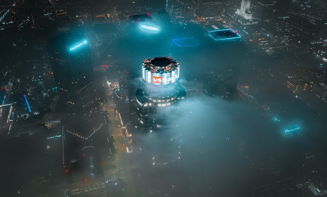 Aerial view of massive futuristic data center campus at night with glowing blue server lights, Chinese flag hologram overlay, professional tech infrastructure, ambient cool lighting, sleek modern arch