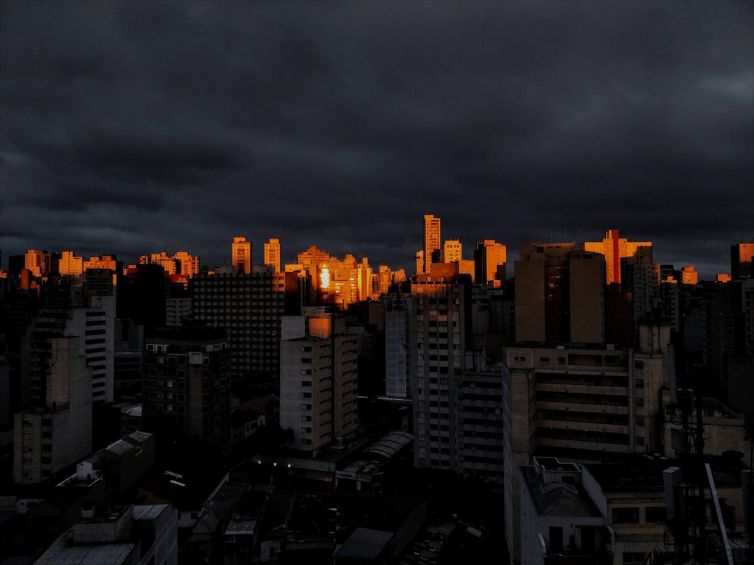 Futuristic small-town Brazilian cityscape merging with holographic neural network overlays, ambient blue lighting, professional tech magazine aesthetic, human silhouette observing data streams
